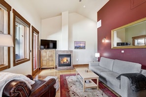 A living room with a fireplace, a sofa, a television, and a large mirror. - RARE One Bedroom Condo w/Private Hot Tub on Main Street (Frisco)