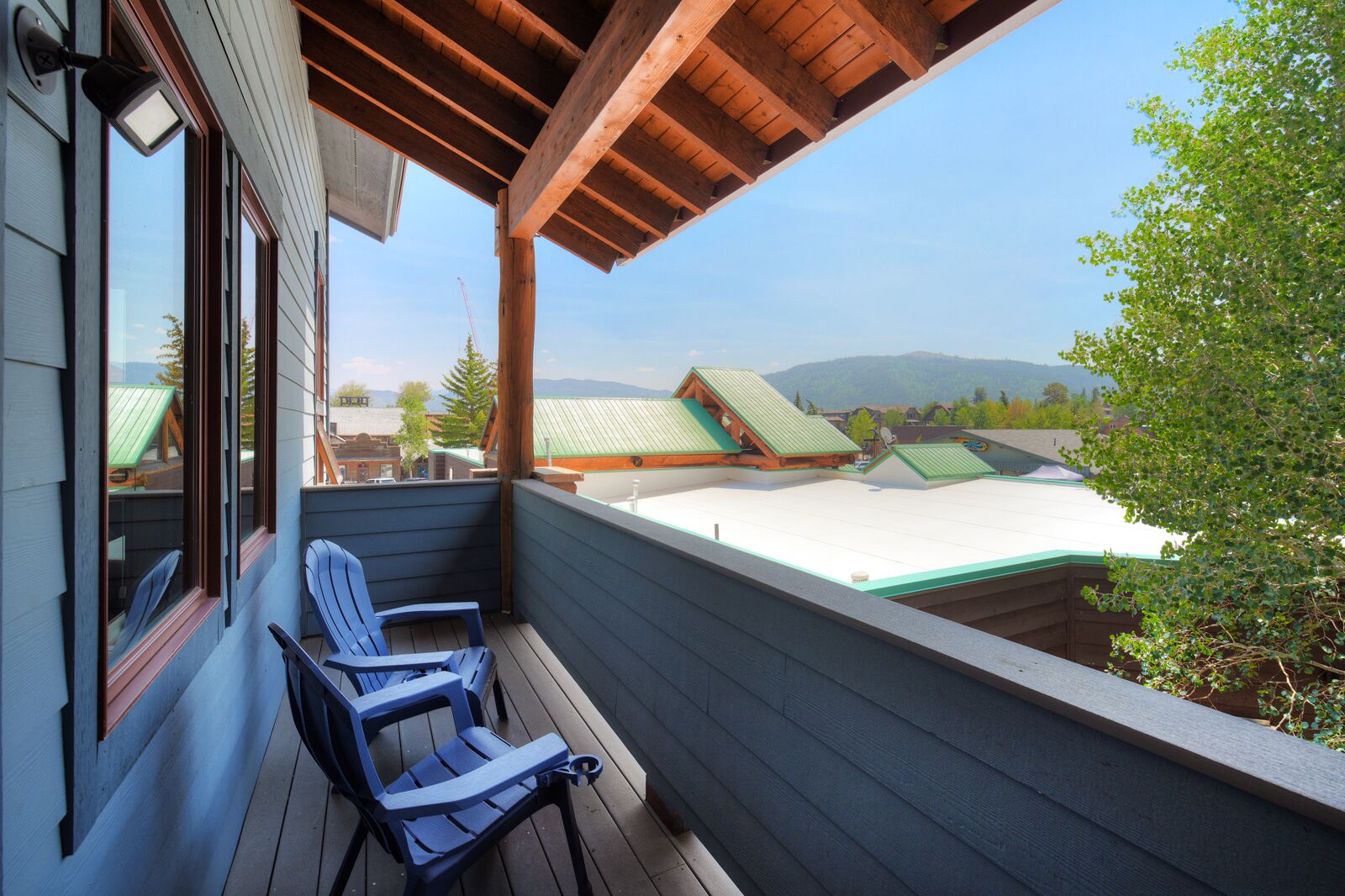 A wooden deck with two chairs, overlooking a mountain landscape with buildings.