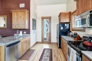 A kitchen with wooden cabinets, stainless steel appliances, and a view to a balcony. - RARE One Bedroom Condo w/Private Hot Tub on Main Street (Frisco)