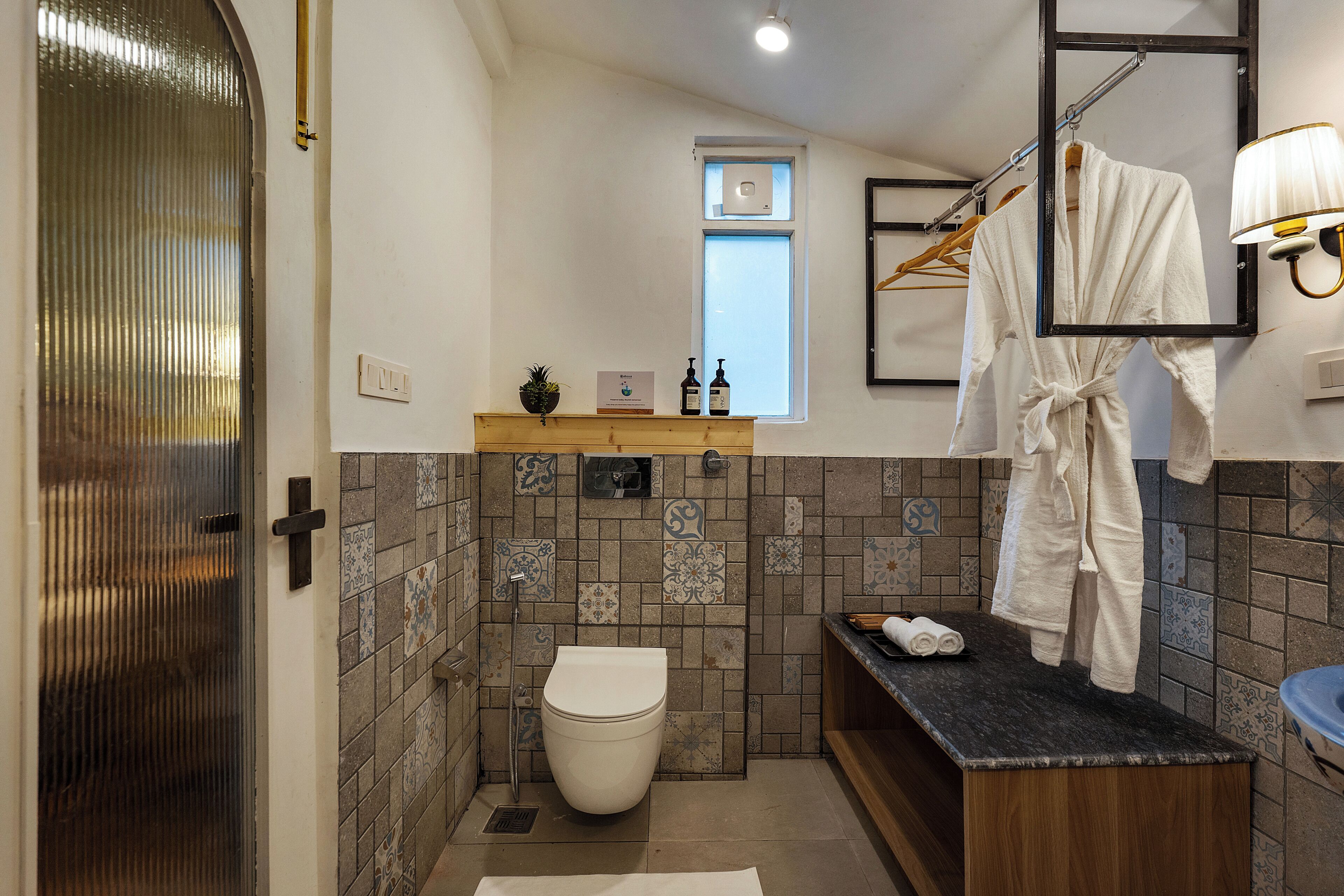 Een badkamer met toilet, wastafel en spiegel. Handdoekrek met handdoeken en een klein raam.