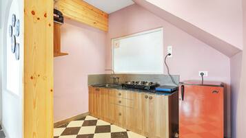 Eine kleine Küche mit Holzausstattung, einem Gasherd, einem roten Kühlschrank und einem karierten Boden.