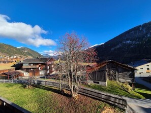 Ein ländliches Dorf mit traditionellen Holzbauten, einem klaren Himmel und Bergen im Hintergrund.