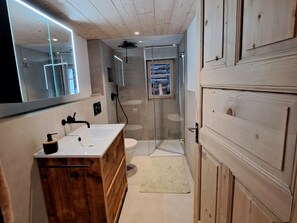 Une salle de bain moderne avec un meuble-lavabo en bois, une cabine de douche en verre et un grand miroir.