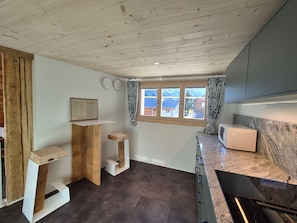 Eine Küche mit Holzbalken, einem fenster mit Vorhängen und einer Mikrowelle auf der Arbeitsfläche.