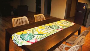 A dining table with a floral table runner, surrounded by chairs. - Bula Accommodation (Nadi)