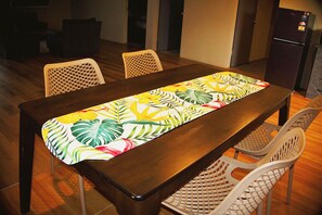 Una mesa de comedor con camino de mesa floral, rodeada de sillas.