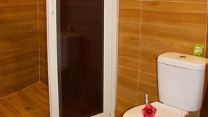 Een badkamer met een douchecabine, toilet en houten vloer.