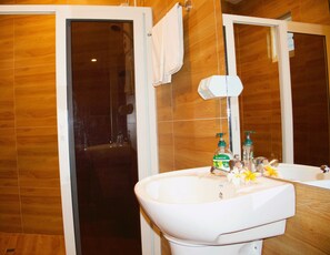 Un baño con un lavamanos blanco, un espejo y una zona de ducha.