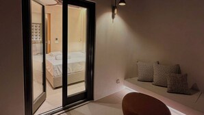 Una habitación moderna con cama, una banca y una lámpara fijada a la pared.