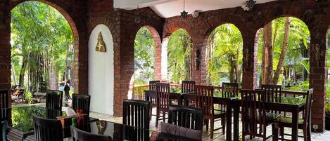 A restaurant with brick arches, wooden tables, and hanging lanterns.