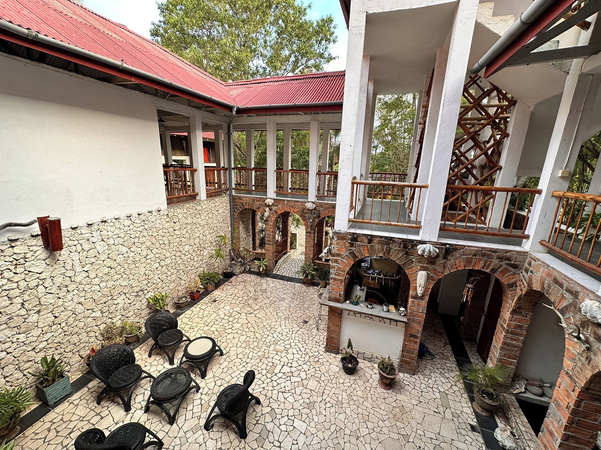 A courtyard with stone flooring, outdoor seating, and a brick fireplace.