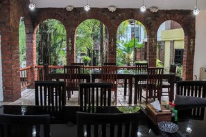 An outdoor seating area with brick arches, wooden chairs, and tables.