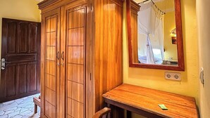A room with a wooden wardrobe, a small wooden table, and a mirror on the wall. - Mangga Lodge (Bira)