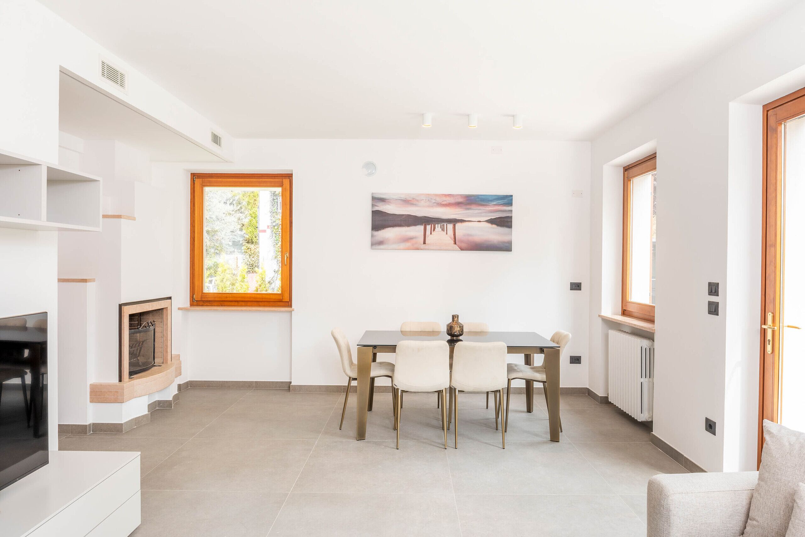 Un comedor con una mesa, sillas, una chimenea y un cuadro en la pared.