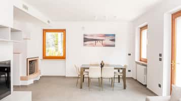 Un comedor con una mesa, sillas, una chimenea y un cuadro en la pared.
