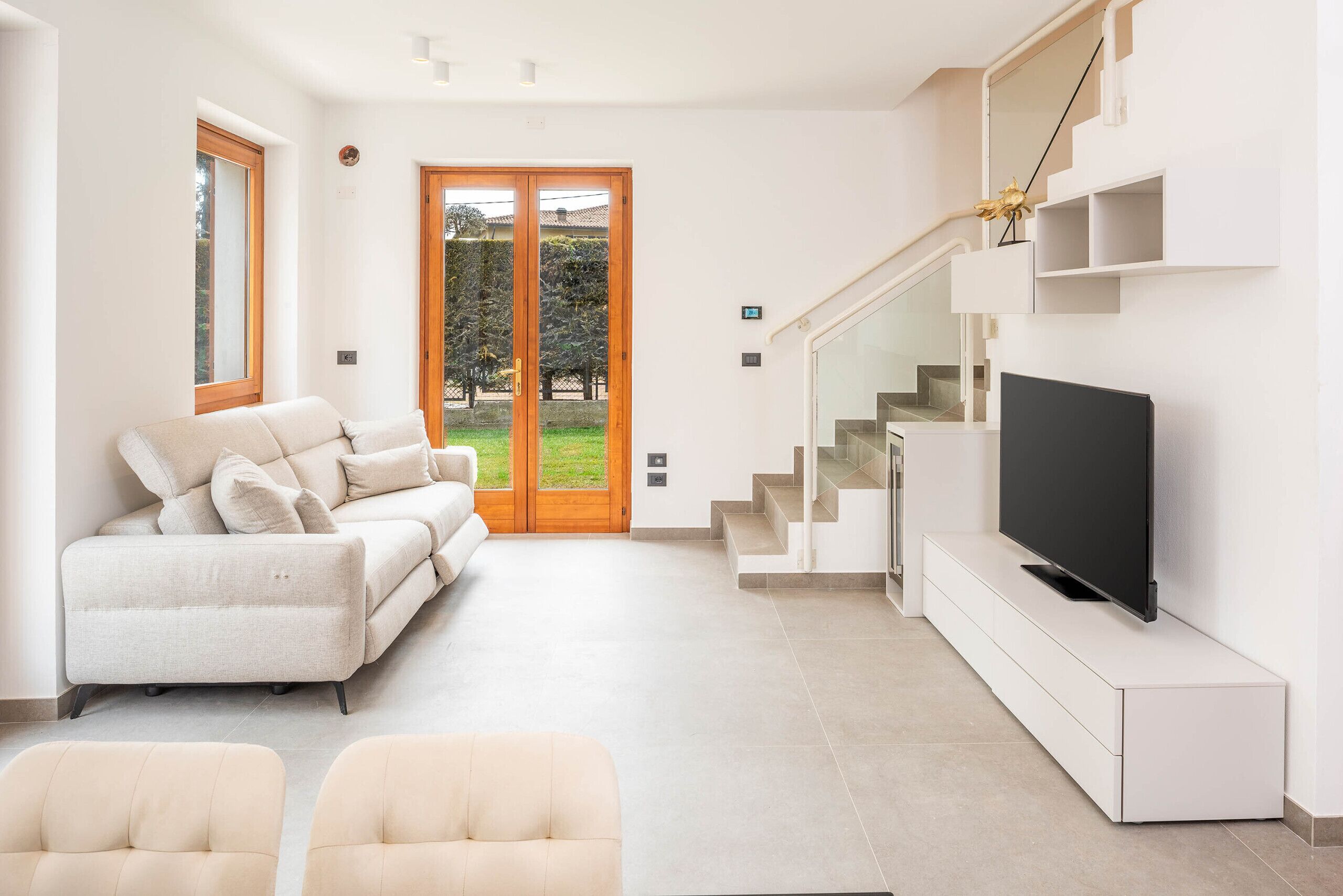 Un salon moderne avec un canapé, un téléviseur et un escalier.