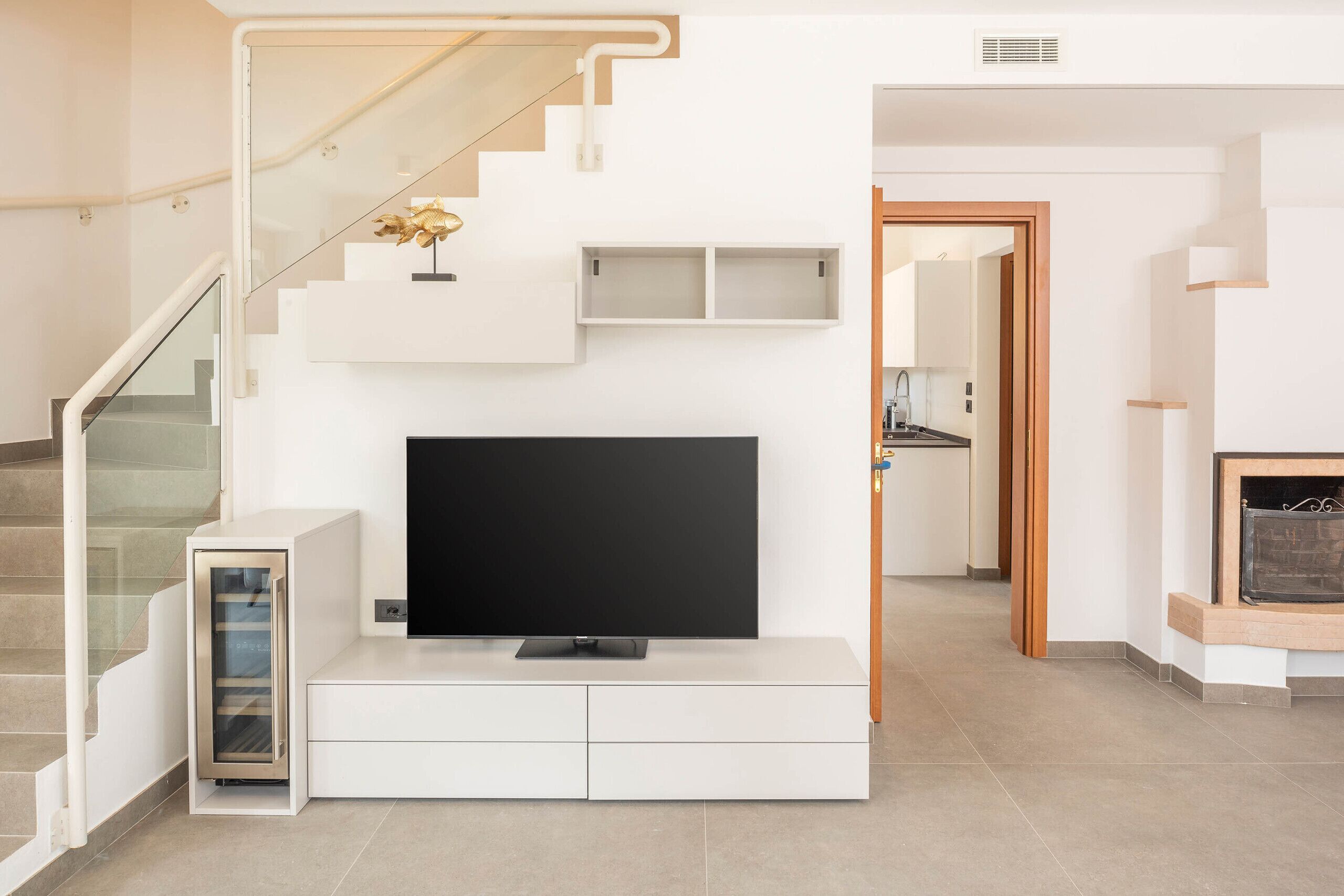 Un salon moderne doté d’un téléviseur à écran plat, d’étagères intégrées et d’un escalier.