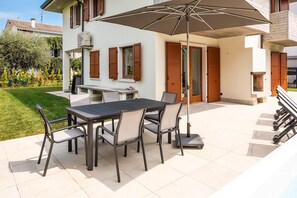 A patio with a table and chairs, an umbrella, and a staircase leading to a balcony.