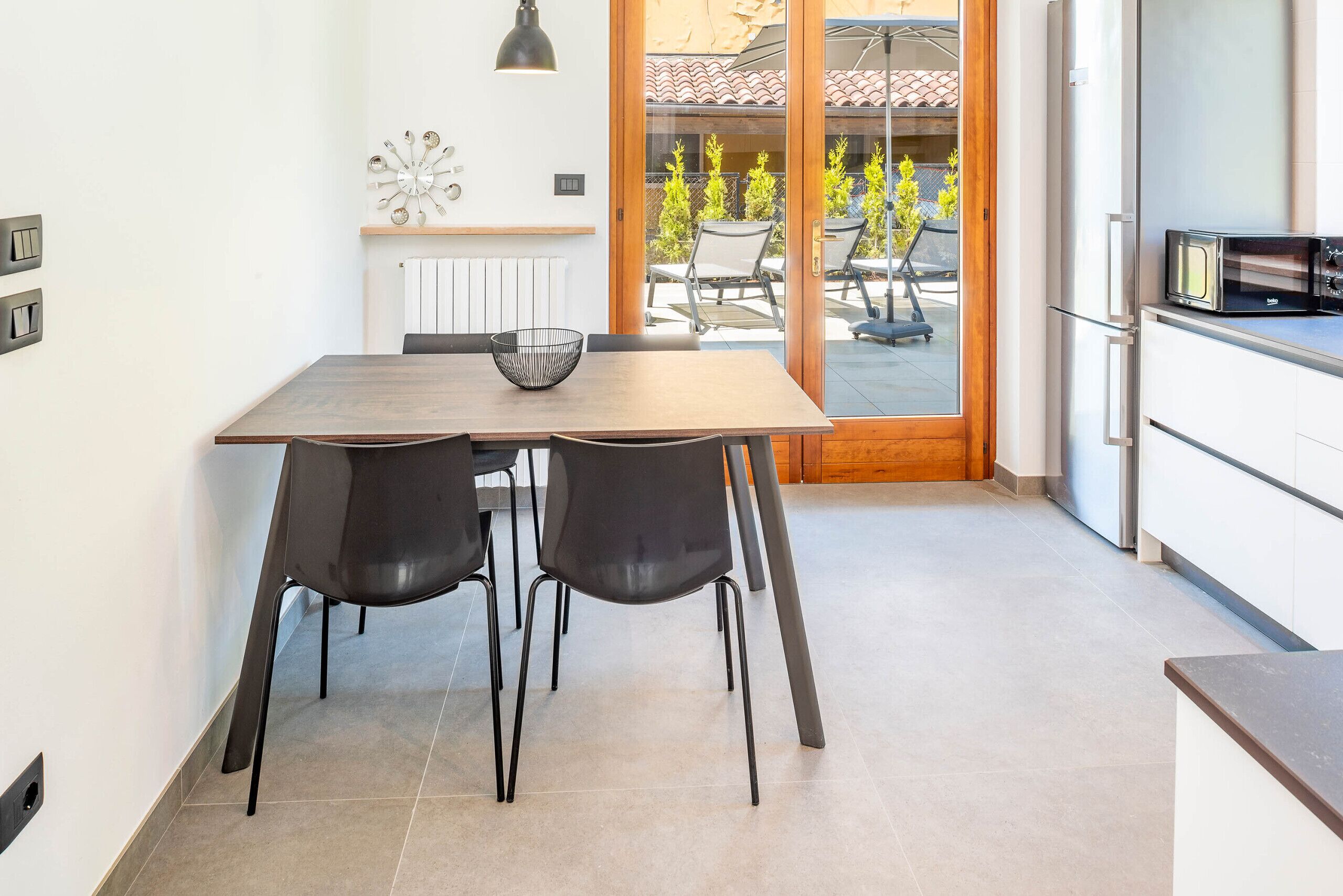Eine moderne Küche mit Essbereich, einem eingebauten Ofen und Blick auf die Terrasse.