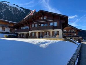 Eine Holzhütte mit Balkon, umgeben von Schnee und Bergen.