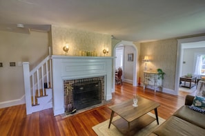 Uma sala de estar com lareira, escada e área de jantar.