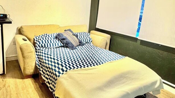 A bedroom with a bed, a bedside table, a wall-mounted air conditioner, and a projector screen. - central stay in cambridge (Cambridge)