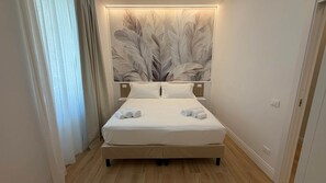 A hotel room with a bed, a headboard with a feather pattern, and a nightstand. - Apollo&Co.House,Perfect Stay before/after cruise,2/4 people (Civitavecchia)