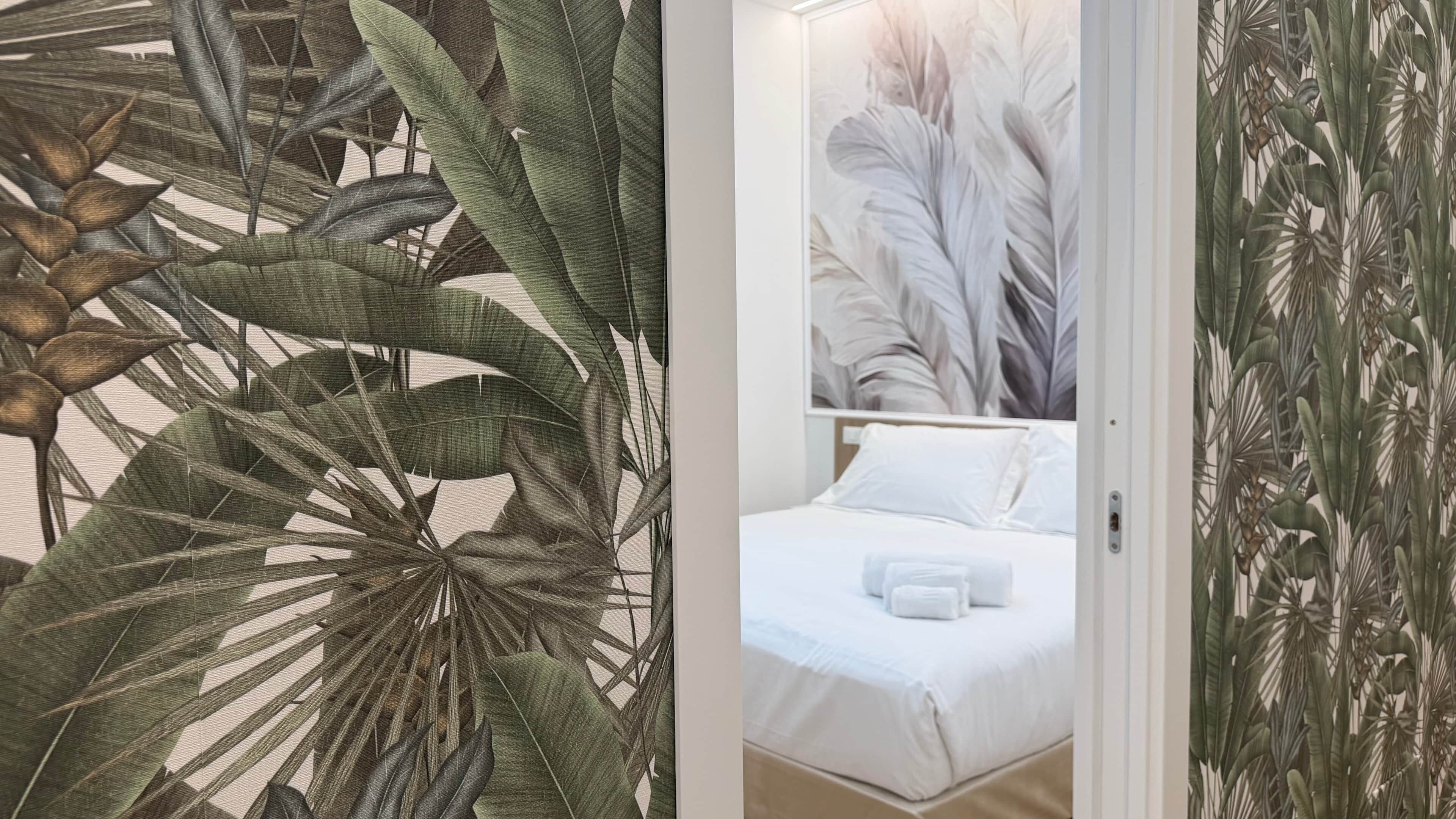 Une chambre avec un lit, du linge de lit blanc et une grande fenêtre.