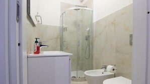 Un baño con ducha envuelta en vidrio, inodoro y lavabo.