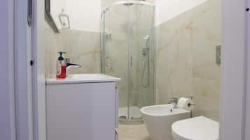 Un baño con ducha envuelta en vidrio, inodoro y lavabo.