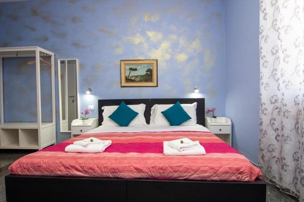 Une chambre d’hôtel avec un lit, deux tables de chevet, une armoire et un tableau au mur.