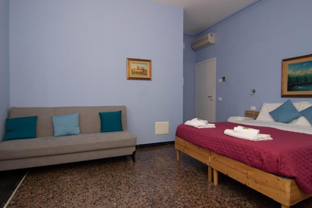 Una habitación con cama, sofá y un cuadro en la pared.