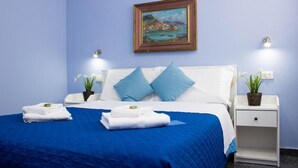 Habitación de hotel con una cama, dos mesitas de noche, un cuadro y una pared azul.