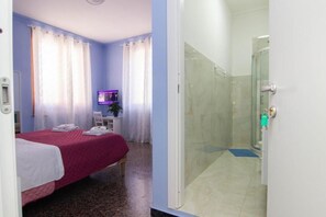A hotel room with a bed, a television, a desk, and a shower area. - B&B CORSO ITALIA (Pisa)