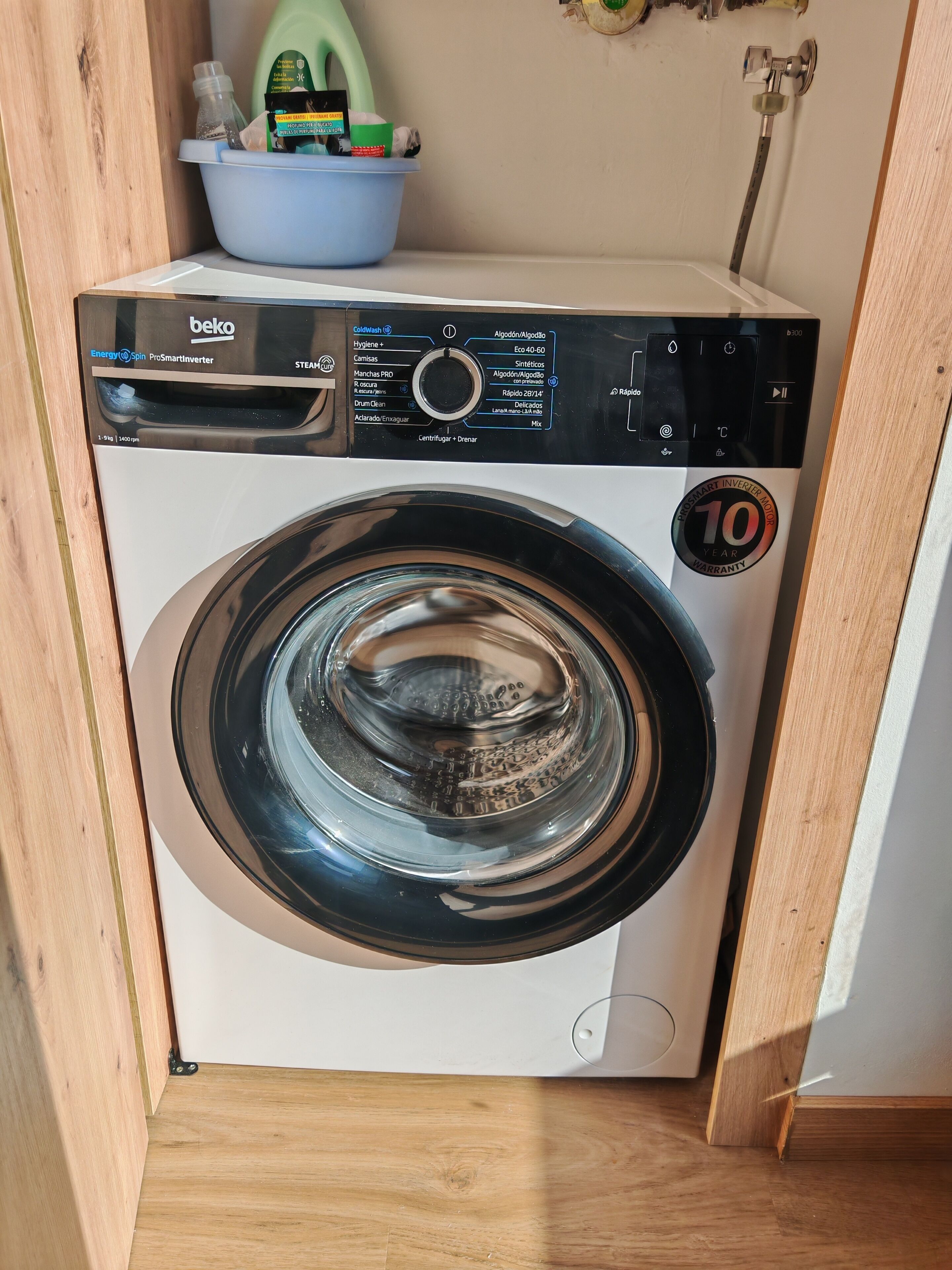 Een voorlader wasmachine met een sticker voor 10 jaar garantie, geplaatst in een houten kast.