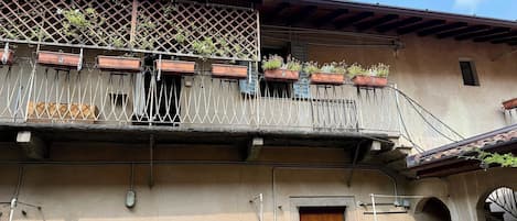 A building with a wooden door, a balcony with potted plants, and a lattice railing.