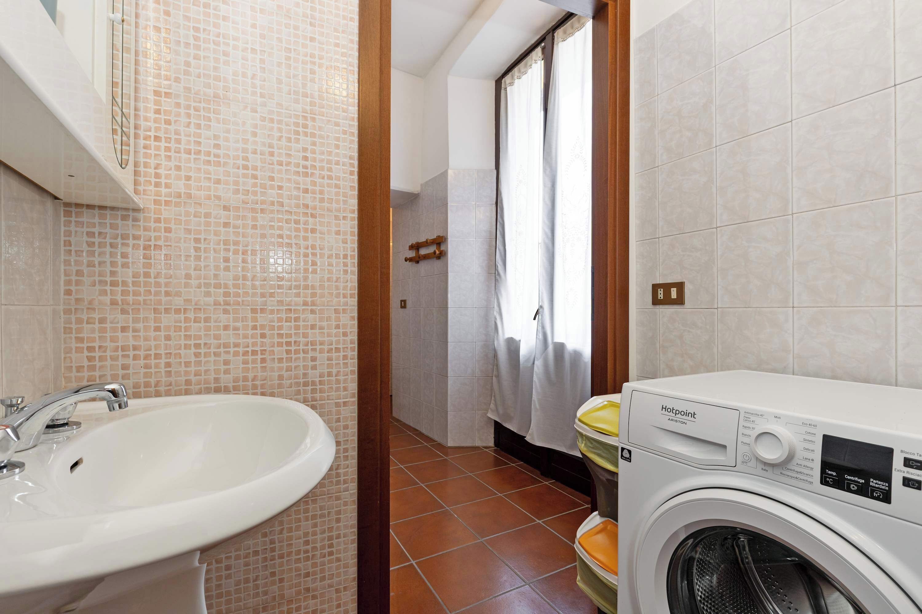 Une salle de bain équipée d’un lavabo, d’un lave-linge et d’un espace douche.