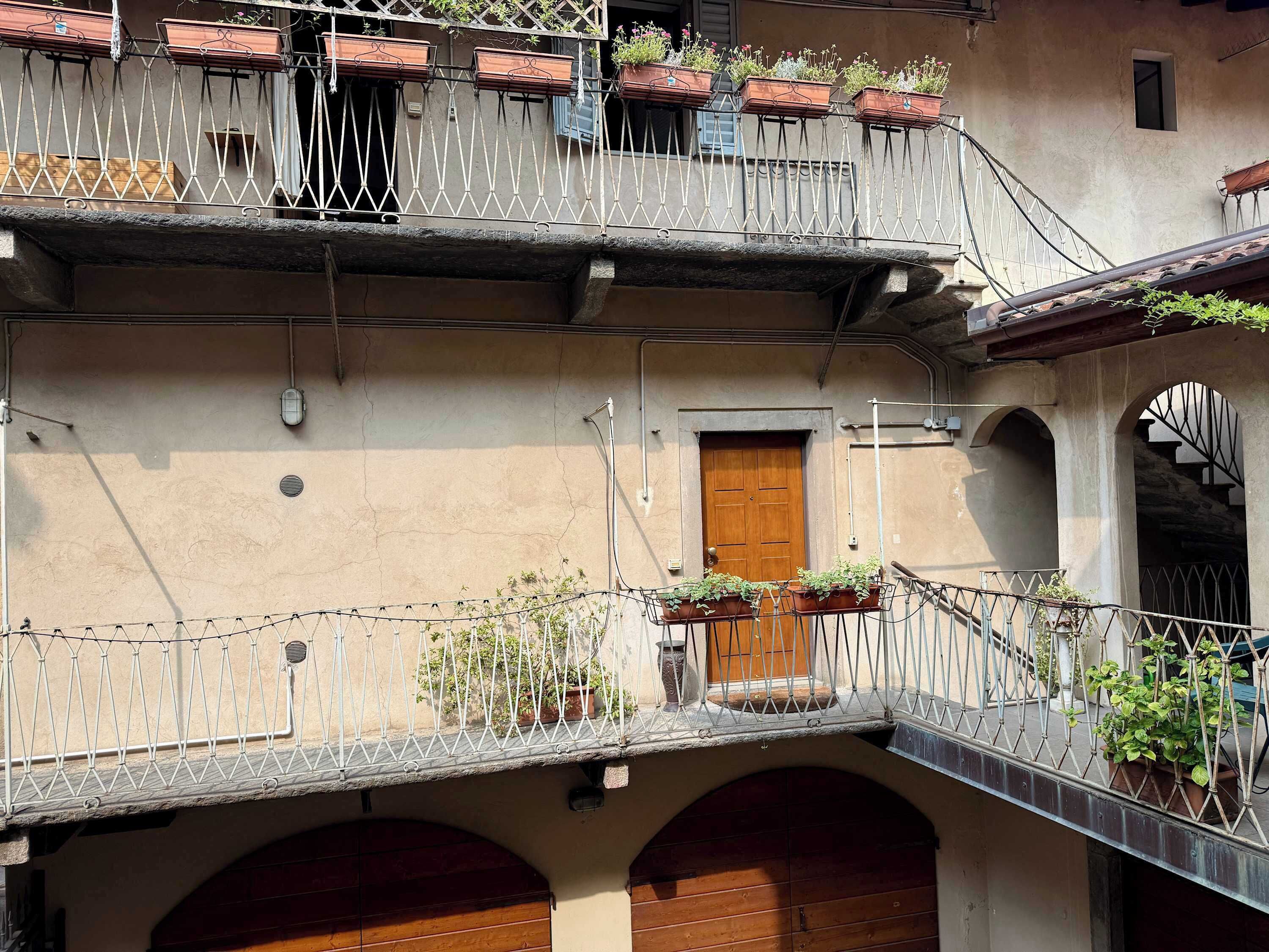 Un edificio de varios pisos con balcones, puertas de madera y plantas en macetas.