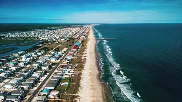 A coastal residential area with a long beachfront, a pier extending into the sea, and a dense cluster of houses. -  Ocean Isle Beach House, Sleeps 11, bike or golfcart distance to the beach (Ocean Isle Beach)