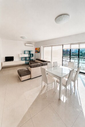 A modern living room with a sofa, a glass dining table, and chairs. - Sunny 3BR Apartment with Coast View - Fl 2 (Naxxar)