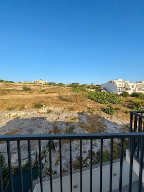 A balcony with a view of a dry, rocky landscape and distant buildings. - Sunny 3BR Apartment with Coast View - Fl 2 (Naxxar)