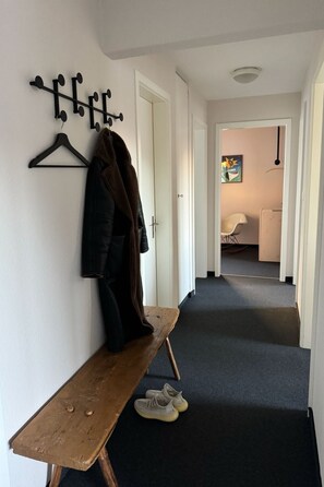 Eine Diele mit Kleiderhaken, einer Bank und einem Schuhpaar.
