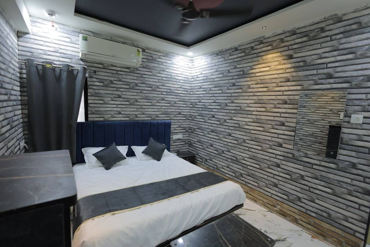 A bedroom with a bed, a headboard, a nightstand, a wall-mounted air conditioner, and a ceiling fan.