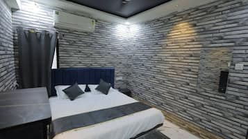 A bedroom with a bed, a headboard, a nightstand, a wall-mounted air conditioner, and a ceiling fan.