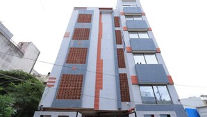 Een meerlaags hotel met een modern ontwerp, met een centraal verticaal element en meerdere balkons.