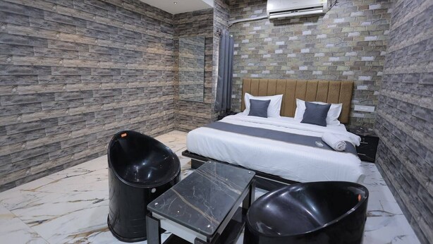 Een hotelkamer met een bed, een klein tafeltje, twee afvalbakken en een airconditioning.