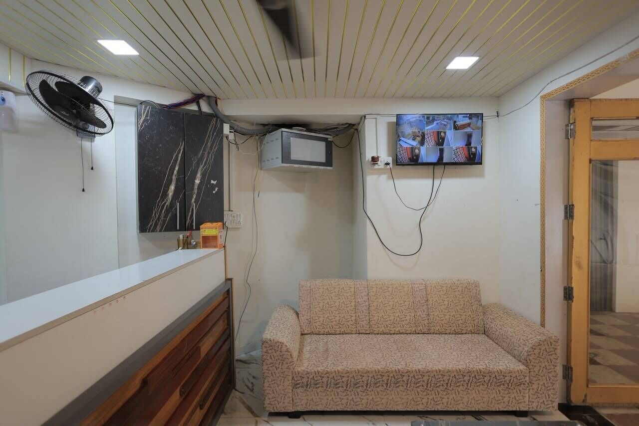 A room with a sofa, a television mounted on the wall, a fan, and a wooden cabinet.