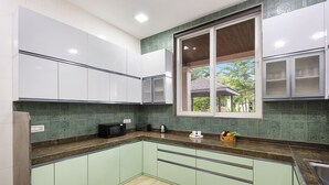 A kitchen with green cabinets, a microwave, a toaster, and a window with a view of the outdoors.