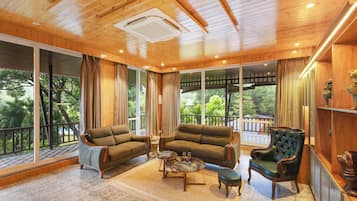 A spacious room with a wooden ceiling, large windows, a sofa set, a coffee table, and a decorative chair.