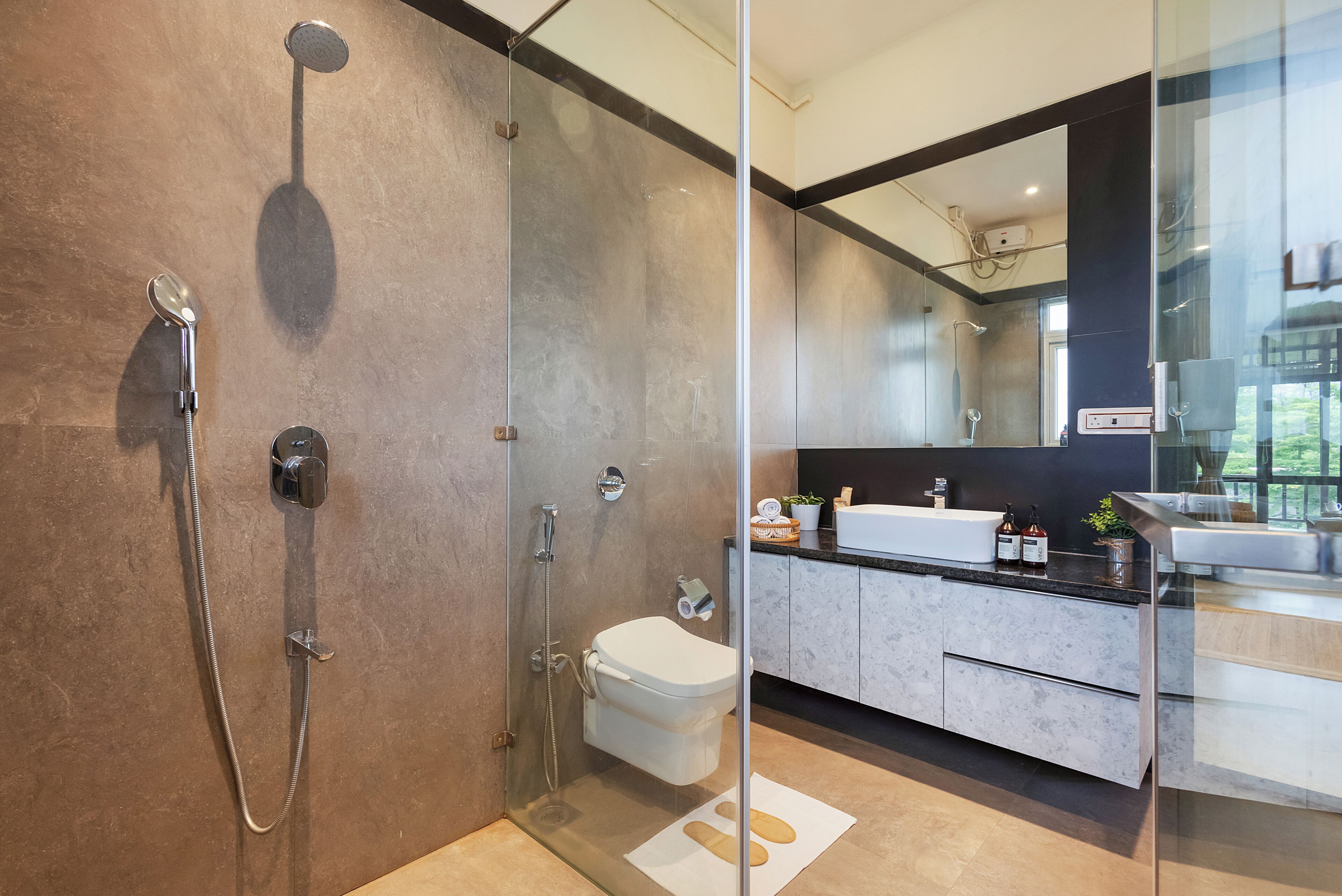 A modern bathroom with a glass-enclosed shower, a white toilet, and a vanity with a mirror.
